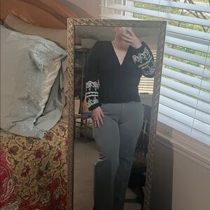 Black long sleeve top with white embroidery on bottom of sleeve